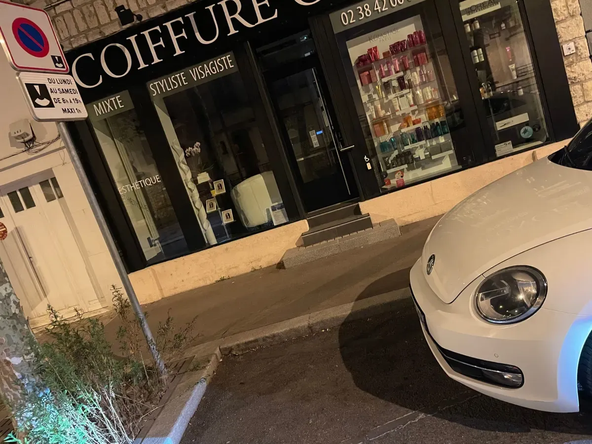 La même devanture photographiée de nuit, l’appareil penché, une voiture garée devant